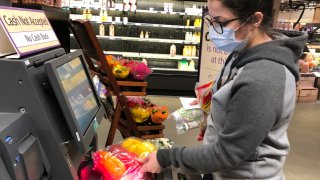 Wearing a surgical mask, Melissa Hall checks out of a Wegmans supermarket