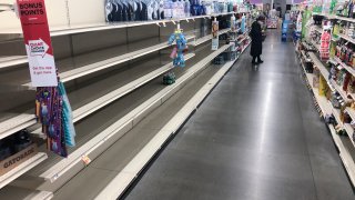 A shopper looks at items near empty shelves at a grocery store in Warrington, Pa., Tuesday, March 17, 2020.