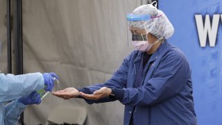 A nurse has hand sanitizer applied on her hands after removing her gloves after she took a nasopharyngeal swab from a patient at a drive-thru COVID-19 testing station