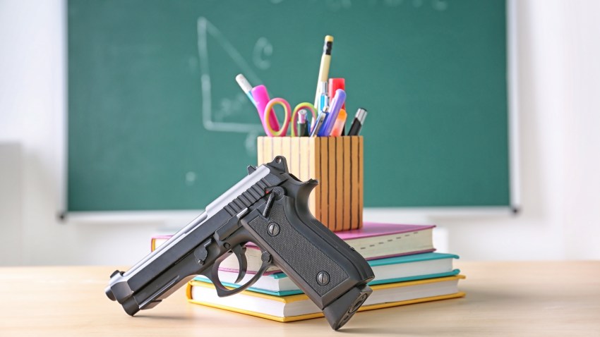 School stationery and gun on table in class