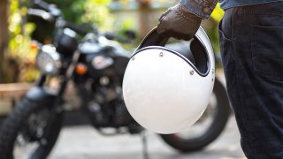 A motorcyclist holds a helmet.