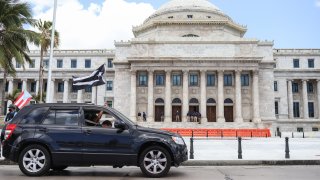 Demonstrators wave a Puerto Rican black flag from a car in front of the heavily guarded Capitol building