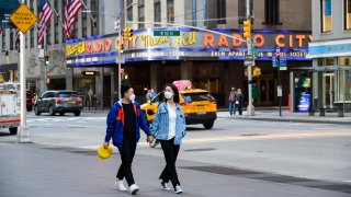 In this May 13, 2020, file photo, people wear protective face masks outside Radio City Music Hall during the coronavirus pandemic in New York City.