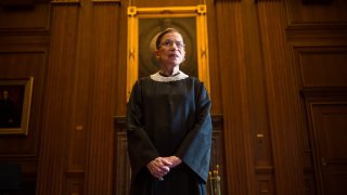Late Supreme Court Justice Ruth Bader Ginsburg stands in robes.