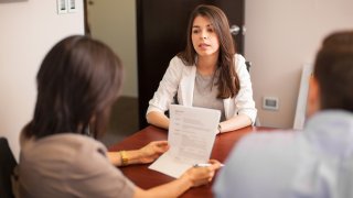 Mujer sentada frente a dos personas que la entrevistan para un empleo.