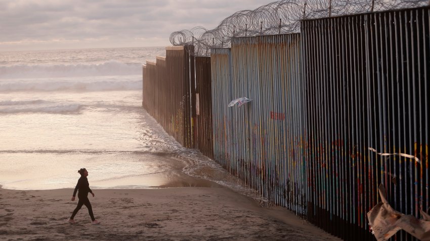 FILE – In this Jan. 9, 2019 file photo, a woman walks on the beach next to the border wall topped with razor wire in Tijuana, Mexico. What started as an online fundraiser to provide President Donald Trump with donations for his southern border wall has morphed into a new foundation whose members vow to build a wall themselves.  The "We The People Will Build the Wall" campaign has surpassed $20 million since it was created in December by Air Force veteran and triple amputee Brian Kolfage. The campaign has received almost 350,000 donations even as wall opponents derided the effort and after the longest government shutdown in U.S. history ended with Congress refusing Trump’s demand for billions in wall funding.