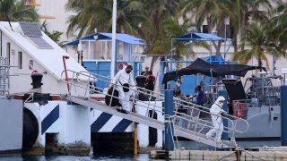 Peritos forenses vestidos de blanco recuperan tres cuerpos del mar