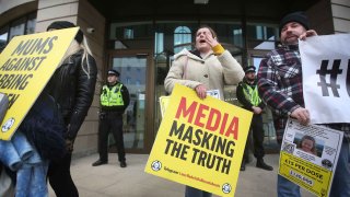 Manifestantes gritan y sostienen un cartel que dice "Medios enmascarando la verdad" mientras la policía impide que se acerquen al edificio del Canal 4 en el Reino Unido.