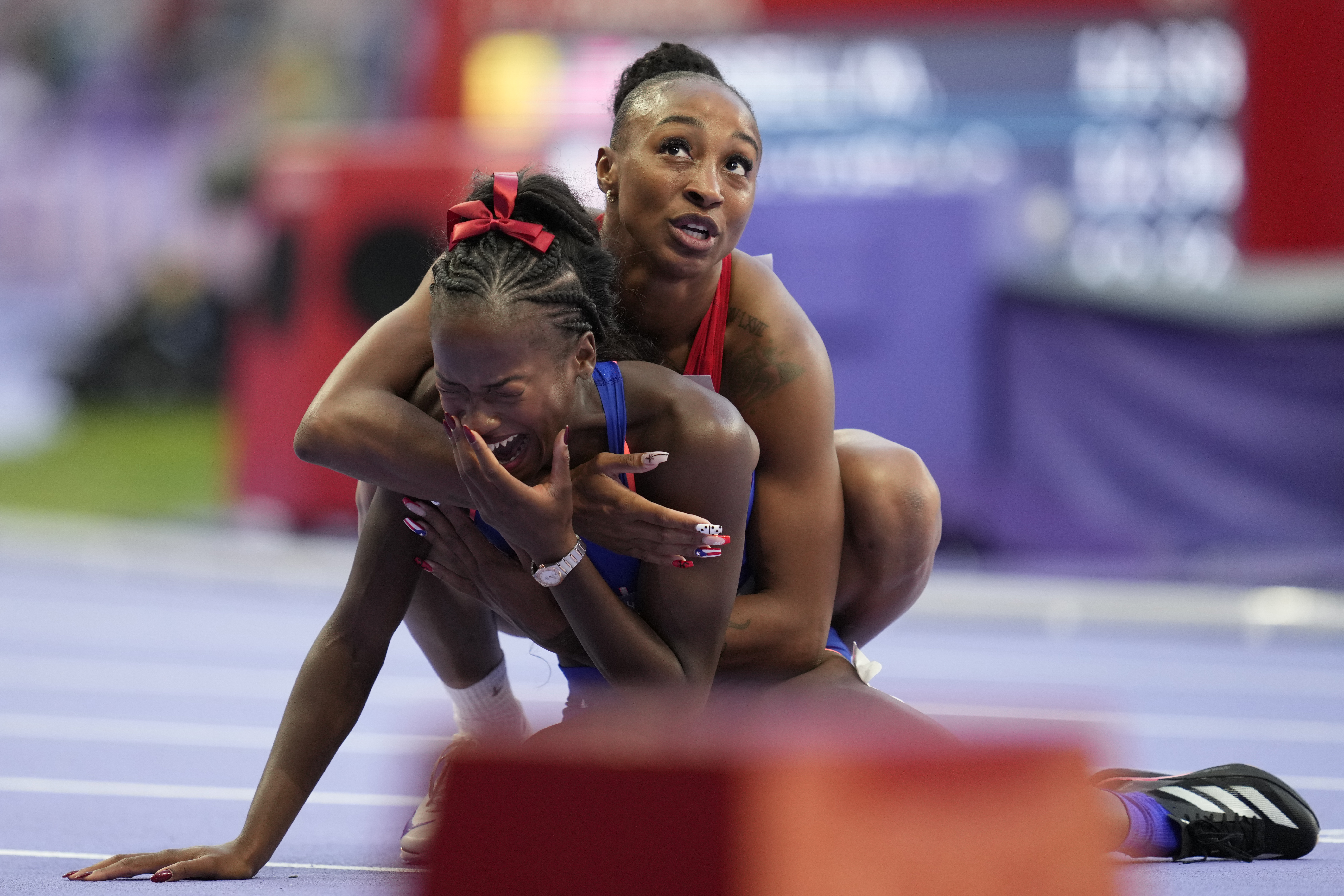 La medallista de bronce Jasmine Camacho-Quinn, de Puerto Rico, abrazó a Cyréna Samba-Mayela, de Francia, después de ganar la medalla de plata en la final femenina de 100 metros (AP Photo/Ashley Landis)