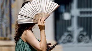 Una mujer se protege del intenso calor con un abanico, en una fotografía de archivo.