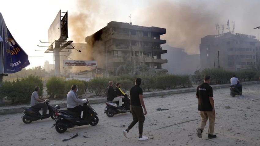 Gente pasa ante edificios destruidos que fueron alcanzados por bombardeos israelíes en Dahiyeh, Beirut, Líbano, el domingo 6 de octubre de 2024.