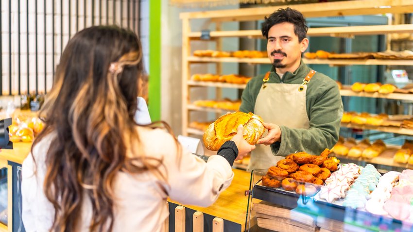 Rear view of a female elegant client buying bread in an artisan bakery shop