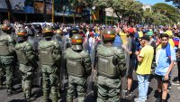 Members of the Venezuelan National Bolivarian guard stand next to demonstrators during a protest called by the opposition on the eve of the presidential inauguration in Valencia, Carabobo state, Venezuela on January 9, 2025. Venezuela is on tenterhooks facing demonstrations called by both the opposition and government supporters a day before President Nicolas Maduro is due to be sworn in for a third consecutive term and despite multiple countries recognizing opposition rival Edmundo Gonzalez Urrutia as the legitimate president-elect following elections past July. (Photo by Jacinto Ontivero / AFP) (Photo by JACINTO ONTIVERO/AFP via Getty Images)