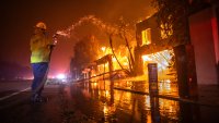 LOS ANGELES, CALIFORNIA – JANUARY 8: A firefighter battles the Palisades Fire while it burns homes at Pacific Coast Highway amid a powerful windstorm on January 8, 2025 in Los Angeles, California.  The fast-moving wildfire has grown to more than 2900-acres and is threatening homes in the coastal neighborhood amid intense Santa Ana Winds and dry conditions in Southern California. (Photo by Apu Gomes/Getty Images)