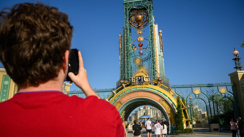 A guest takes a photograph at the entrance portal to the Epic Universe theme park in Orlando, Florida, US, on Saturday, April 5, 2025. Epic Universe, the $7 billion attraction from Comcast Corp.’s Universal Destinations & Experiences division, offers five distinct lands and opens to the public on May 22. Photographer: Thomas Simonetti/Bloomberg via Getty Images